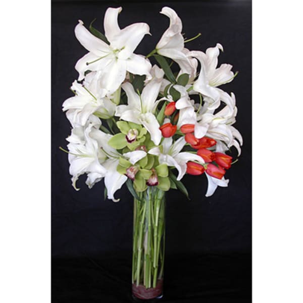 White lilies and red tulips arranged in a tall glass vase