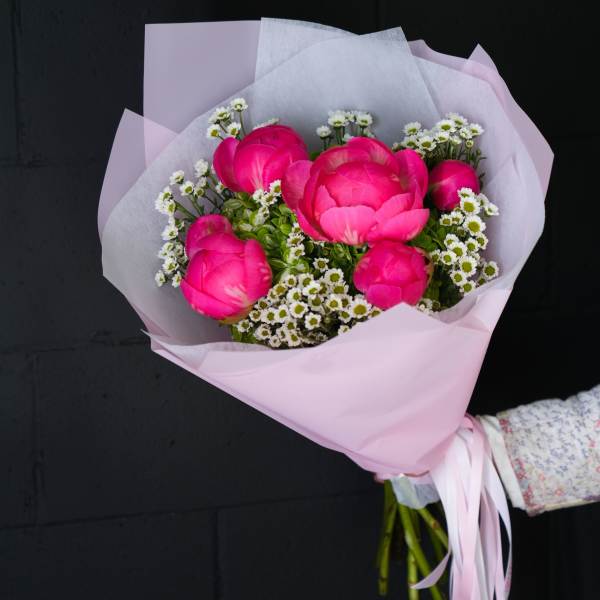 Bouquet of bright pink peonies with small white filler flowers