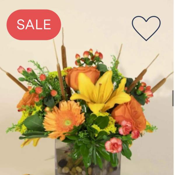 Orange and yellow floral arrangement in a square glass vase