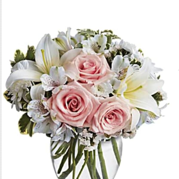 Pink roses and white lilies arranged in a clear glass vase