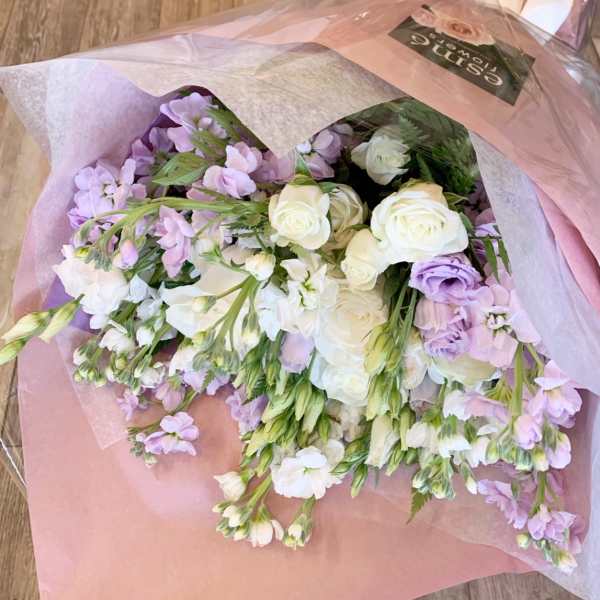 Bouquet of white roses and lavender flowers wrapped in pink paper