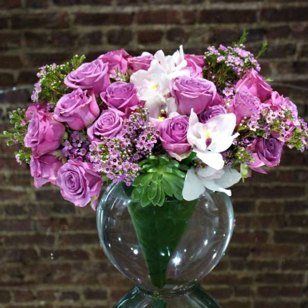 Pink rose bouquet with white orchids in a clear glass vase
