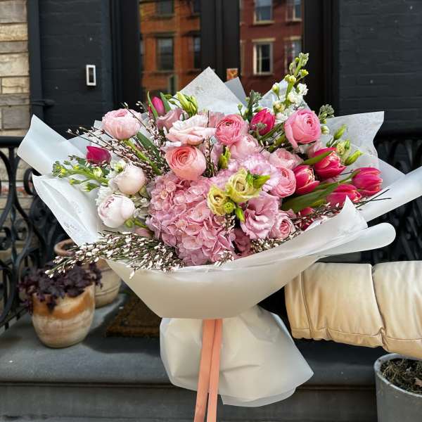 Large pink bouquet wrapped in white paper with a peach ribbon