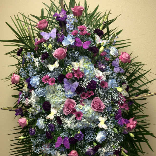 Large standing floral spray with pink and purple flowers and butterfly accents