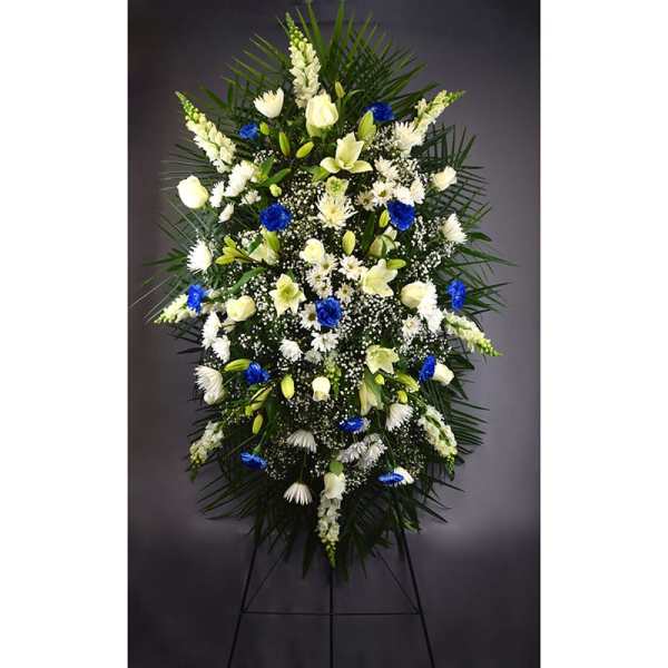 Tall funeral spray of white and blue flowers on a stand