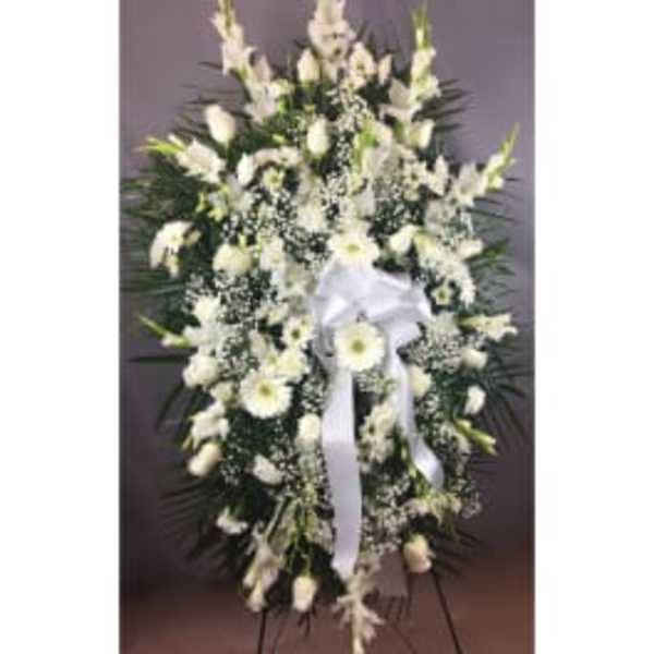 White funeral spray with ribbon and mixed blooms on a standing easel