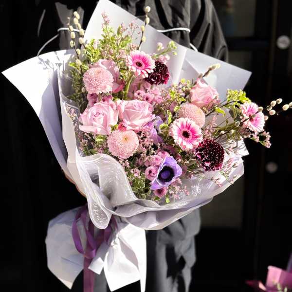 Pink and purple mixed bouquet wrapped in white paper with ribbon