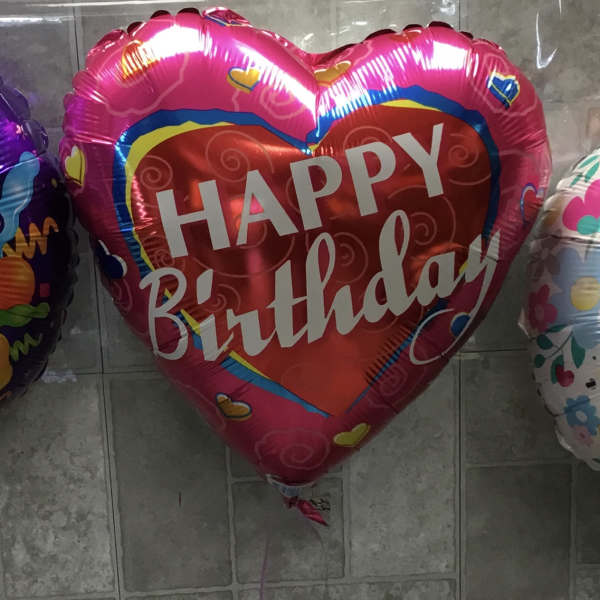 Three birthday balloons in purple, pink, and white.