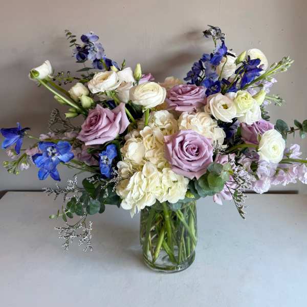 Lavender roses and white blooms in a clear glass vase