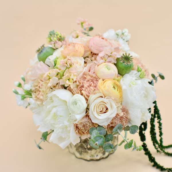 Pastel bouquet of roses, ranunculus, and peonies in a metallic vase