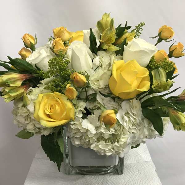 Yellow and white rose bouquet in a clear square vase