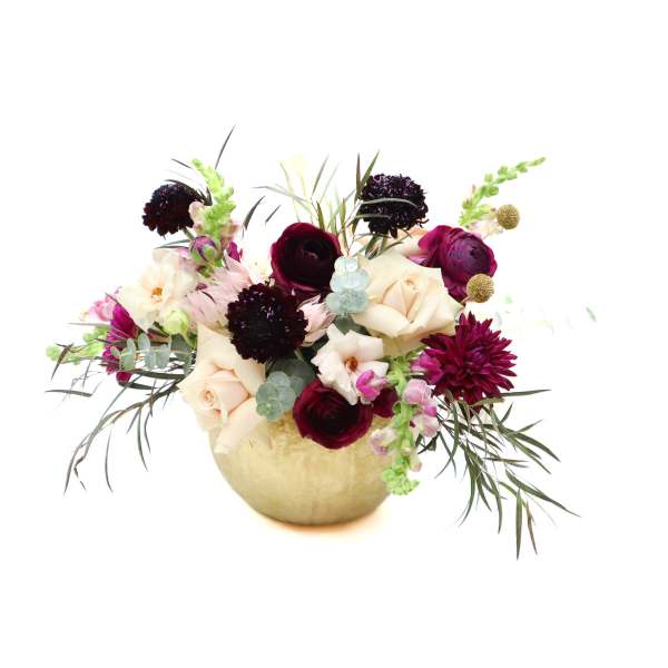Mixed bouquet of cream, burgundy, and pink flowers in a gold vase