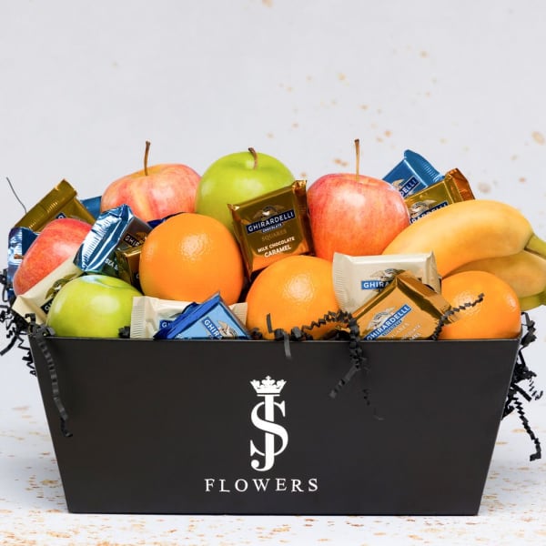 Fruit and chocolate gift box with apples, oranges, bananas, and wrapped candies