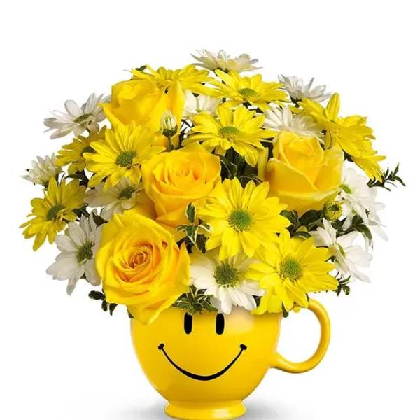 Yellow roses and white and yellow daisies arranged in a yellow smiley-face mug.