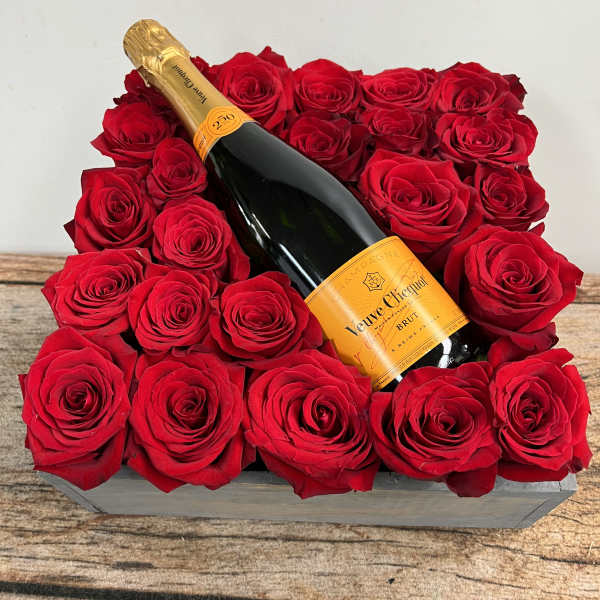 Red roses arranged around a champagne bottle in a rectangular box