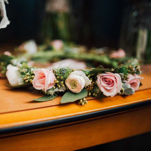 Pink and white floral crown with roses and ranunculus on a table