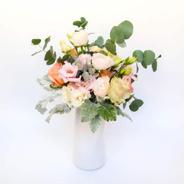Pastel bouquet of roses and ranunculus in a white vase
