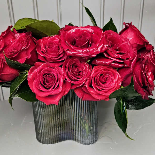 Bright pink roses arranged in a ribbed glass vase
