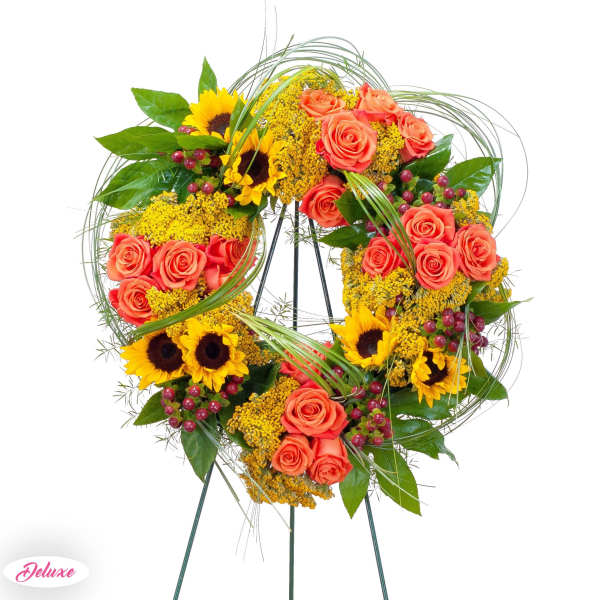Heart-shaped floral wreath with roses and sunflowers on a stand