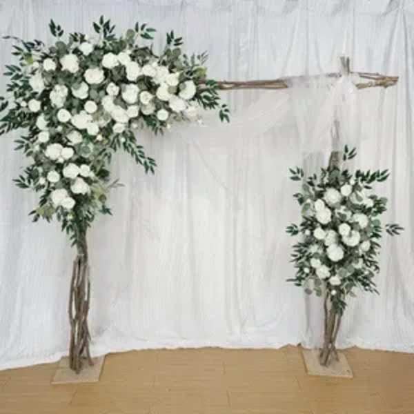 Wedding arch with white roses and greenery on a rustic wooden frame against white draping