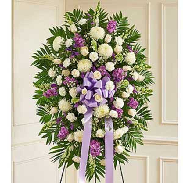 Standing funeral spray of white and purple flowers with a lavender ribbon
