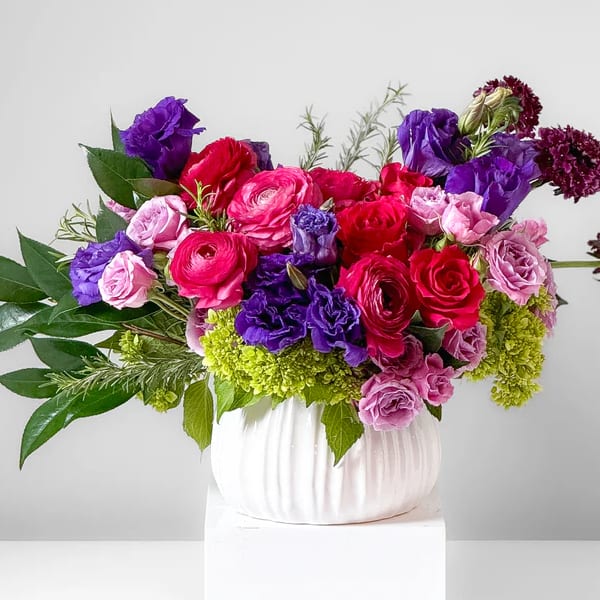 Bouquet of pink, red, and purple flowers in a white vase