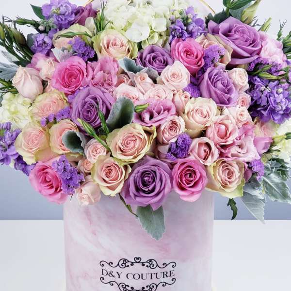 Mixed pink and purple roses in a round hat box
