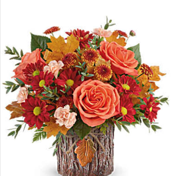 Autumn bouquet of orange roses and red daisies in a bark-covered vase
