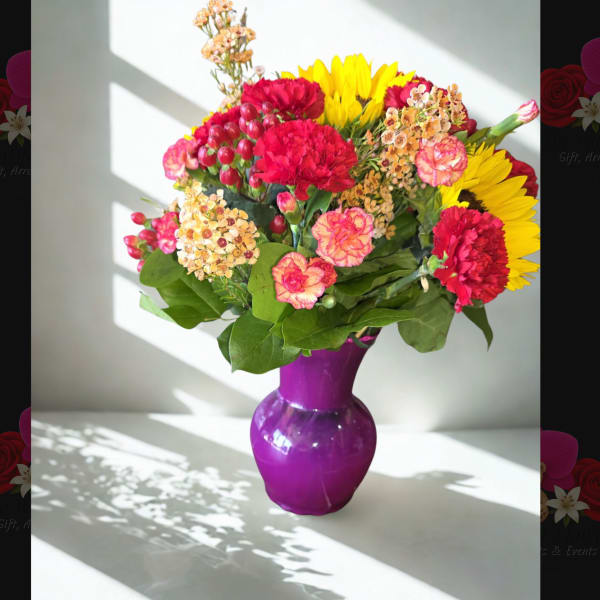 Mixed bouquet of red, pink, and yellow flowers in a purple vase