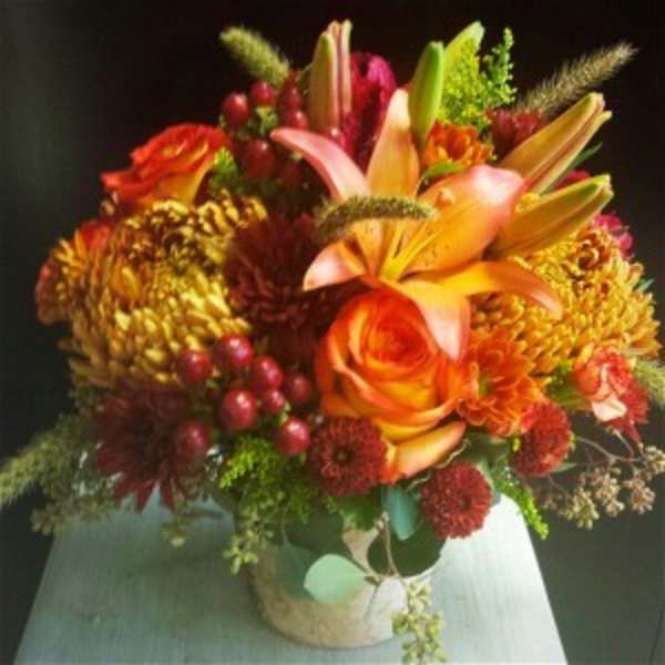 Orange lilies and roses in a low vase arrangement