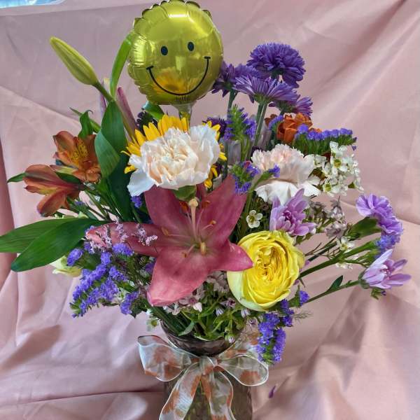 Mixed bouquet in a vase with a smiley-face balloon