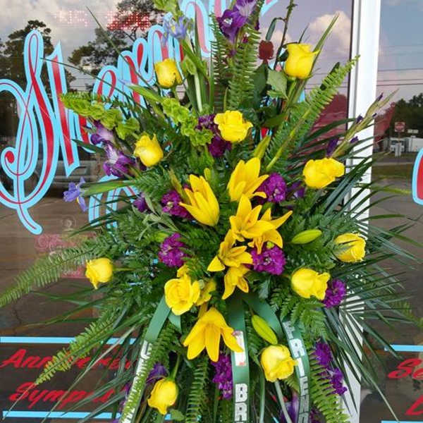 Tall standing floral spray with yellow roses and lilies, accented by purple flowers