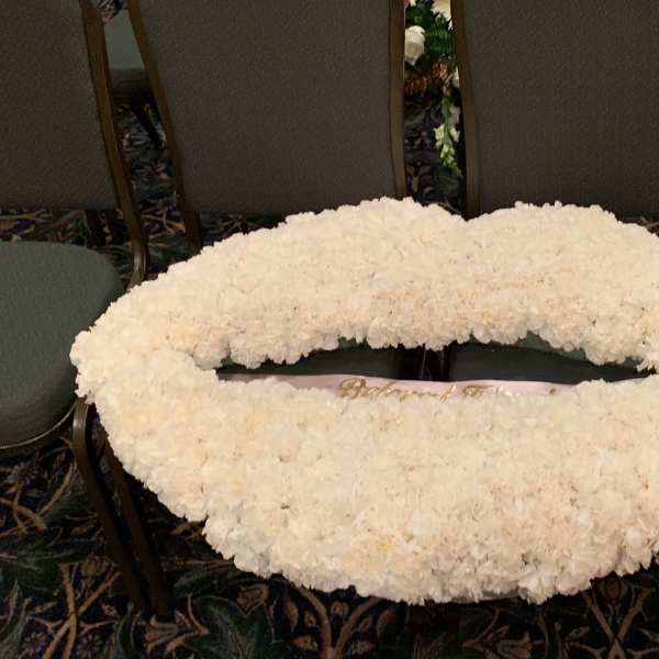 Large white floral wreath laid flat on chairs