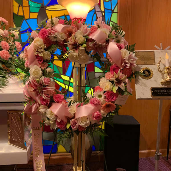 Pink and white floral wreath on a stand with satin ribbons