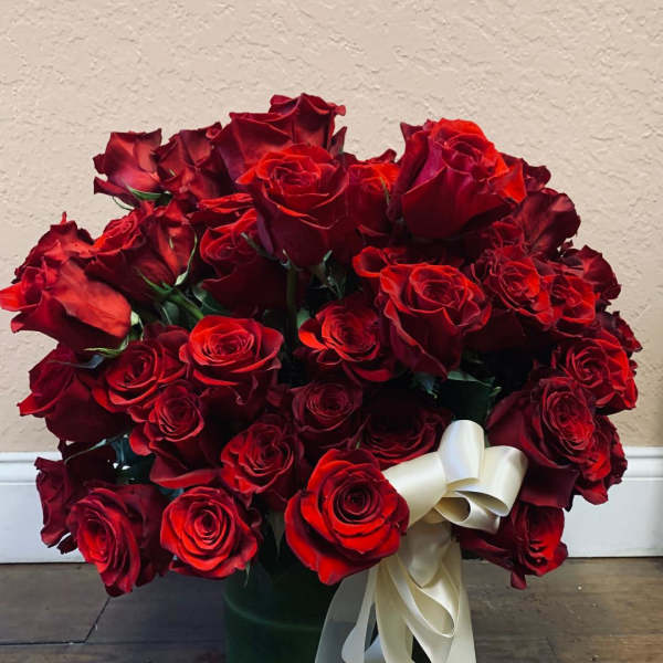 Bouquet of red roses in a glass vase with a white ribbon