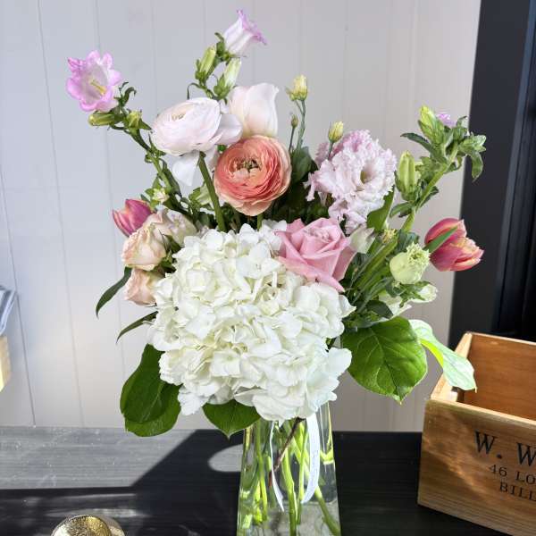 Mixed pink and white flowers arranged in a clear glass vase