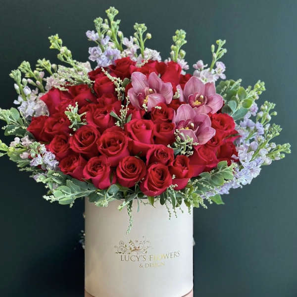 Red roses and pink orchids in a white hat box