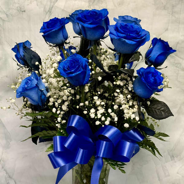 Blue roses in a glass vase with white baby's breath and a blue ribbon