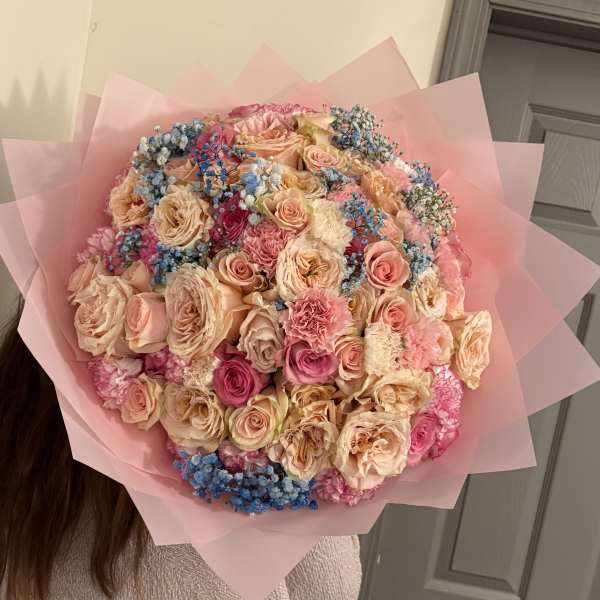 Large bouquet of pink and peach roses with blue filler flowers