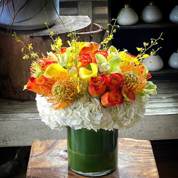 Bouquet of orange and yellow flowers in a green glass vase