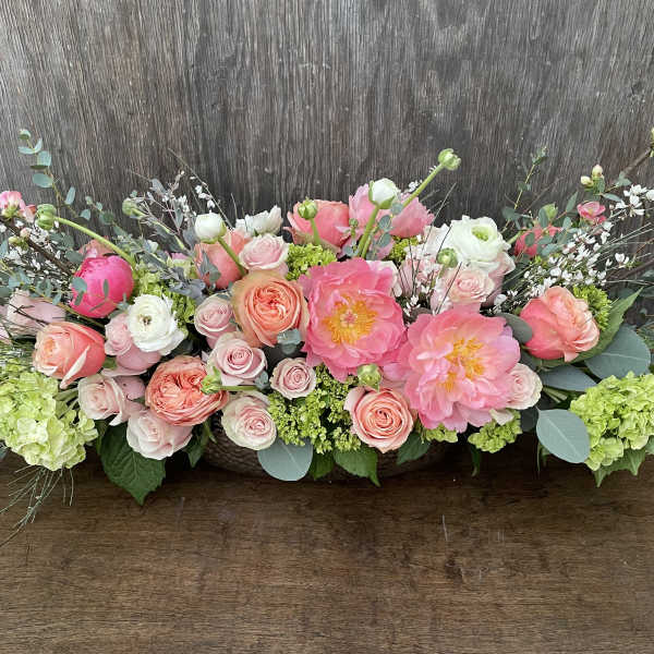 Low floral arrangement of pink and peach roses with large pink blooms