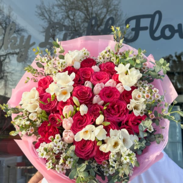 Large bouquet of pink and white roses wrapped in pink paper
