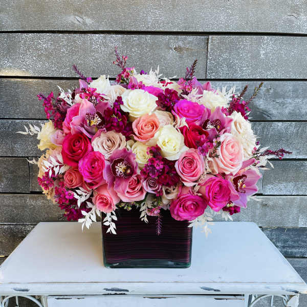 Pink and white rose arrangement in a square glass vase