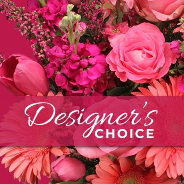Pink floral arrangement with roses and daisies behind a Designer's Choice banner