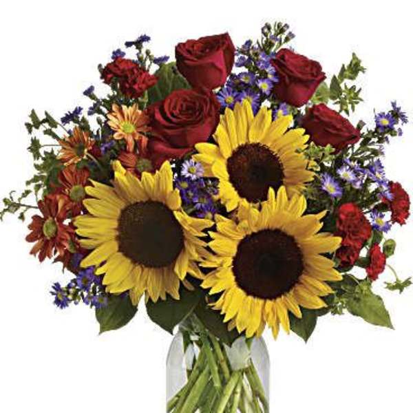 Bouquet of sunflowers, red roses, and purple flowers in a glass vase