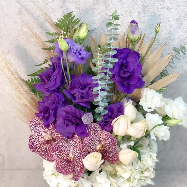 Purple and white bouquet with orchids, roses, and hydrangeas in a vase