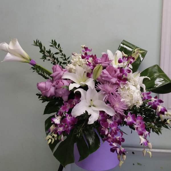 Pink and white floral arrangement in a vase with orchids and lilies