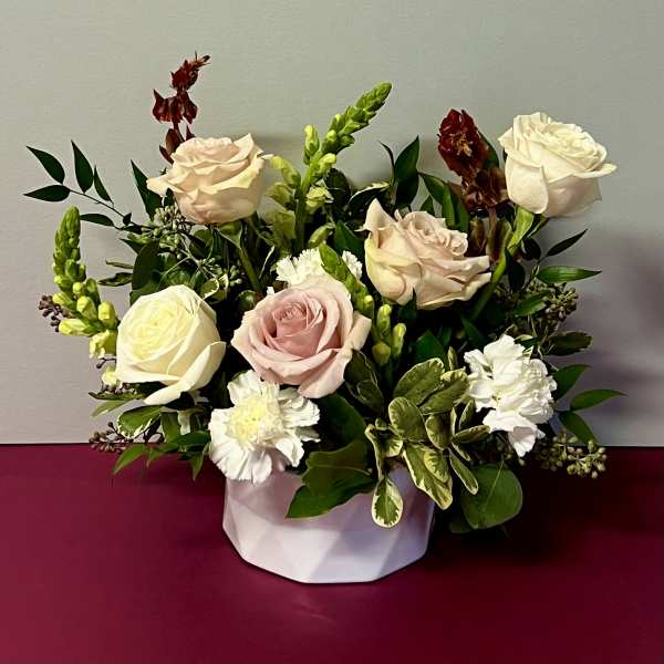 Arrangement of pale roses and white carnations in a white container