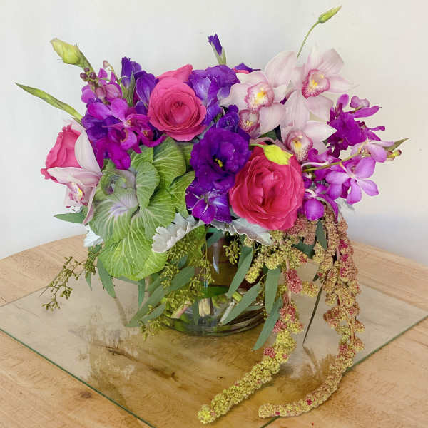 Bright pink and purple floral arrangement in a glass vase