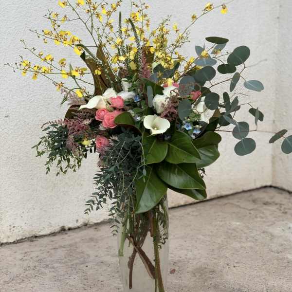 Tall mixed bouquet in a clear glass vase with pink, white, and yellow flowers
